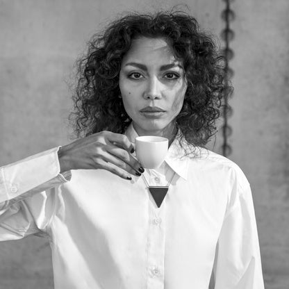 Woman holding an espresso cup against a plain background