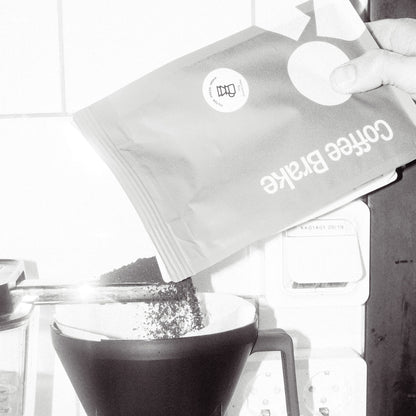 Coffee bag labeled 'Coffee Brake' being poured into a moccamaster.