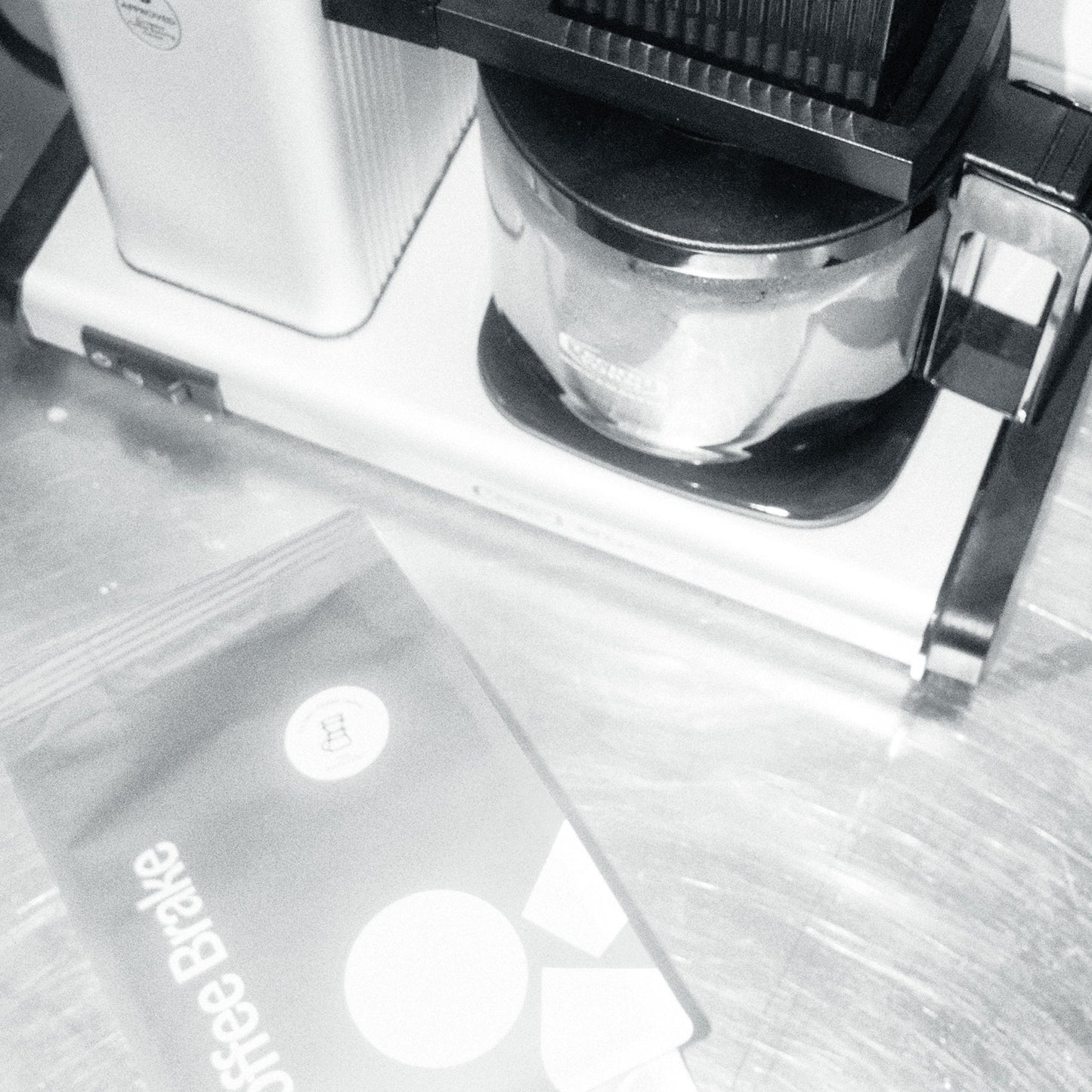 Close-up of a coffee maker with a filter and a bag labeled 'Coffee Brake' on a reflective surface.